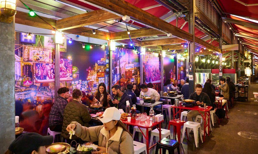 A laneway restaurant with people cooking on hot pots