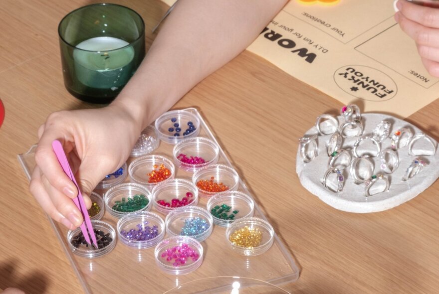 A hand selecting a coloured stone to add to a silver ring in a workshop setting. 
