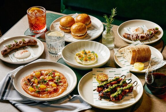 An Italian-American spread on a table featuring shared plates, pasta, and cocktails.