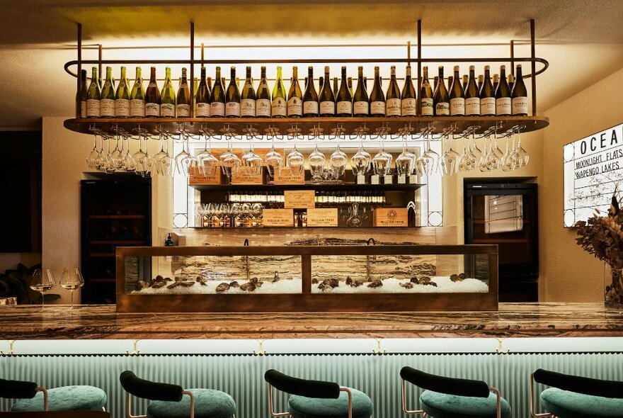 Looking at a small bar with bottles shelved above and an oyster station.