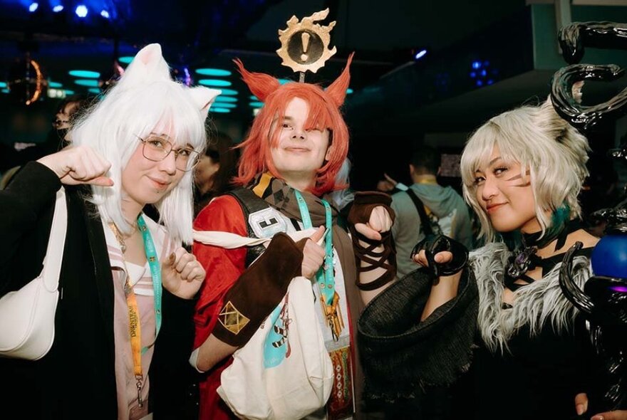 Three people dressed in Final Fantasy XIV cosplay outfits, smiling and posing for the camera.