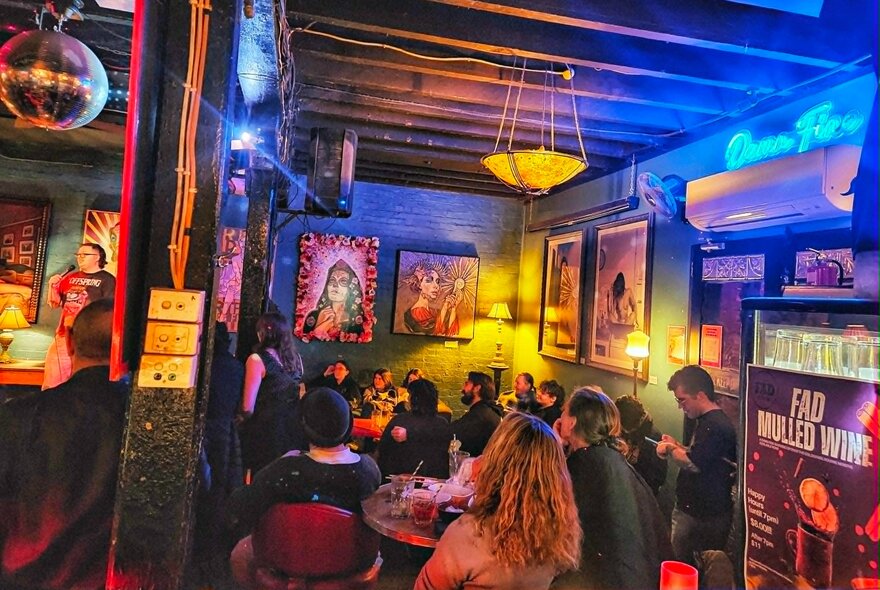 Dimly lit bar with artworks on the walls and eclectic decor.