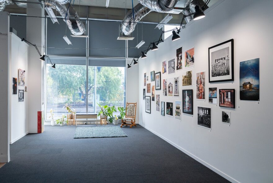 Interior gallery space with white walls densely hung with various framed photos and artworks.