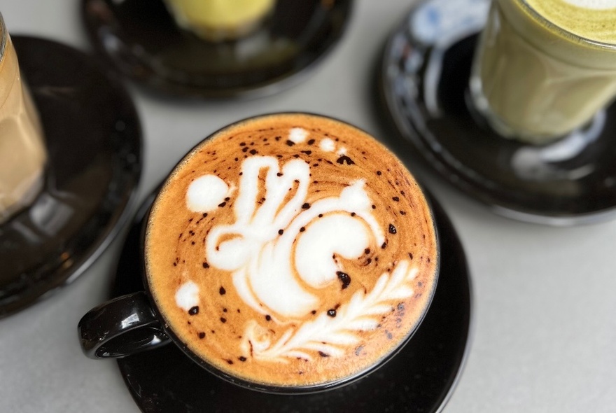 Top view of coffee in black cup, with rabbit milk art.