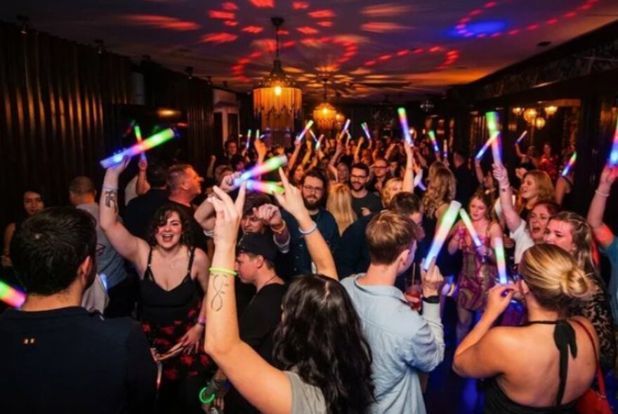 People dancing with fluro banners in a nightclub.