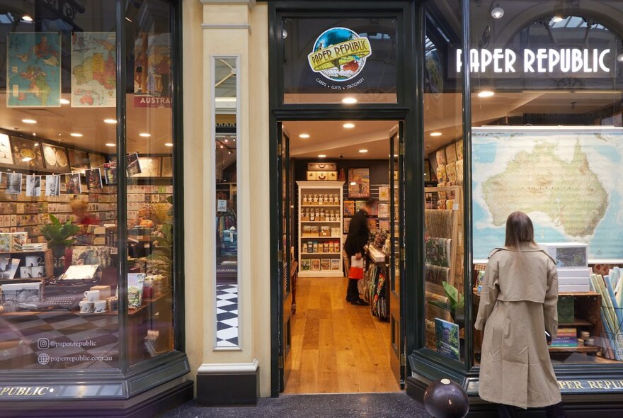 The facade of hand-crafted stationery store, Paper Republic, with a woman in a beige trench coat looking at the window.