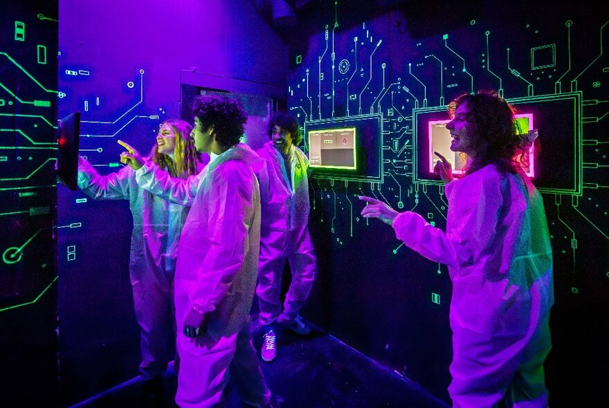 People in a purple-lit arcade games room with wall computeres.
