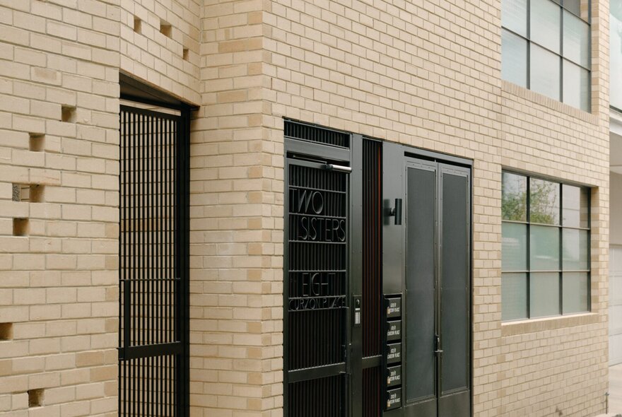 The exterior cream brick facade and security gate of 'Two Sisters, a residential development located in North Melbourne.