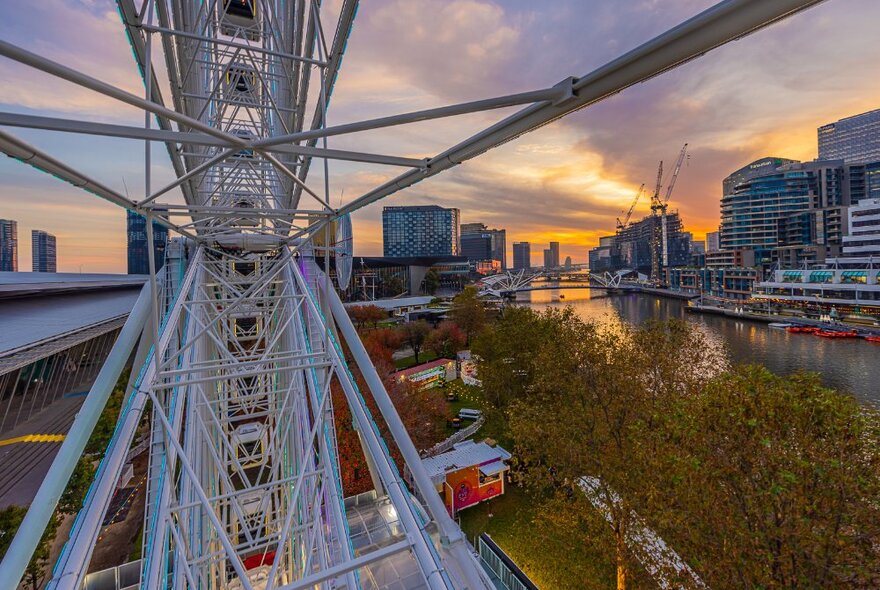 A view of the sunset over the river from a ferris wheel in the city.