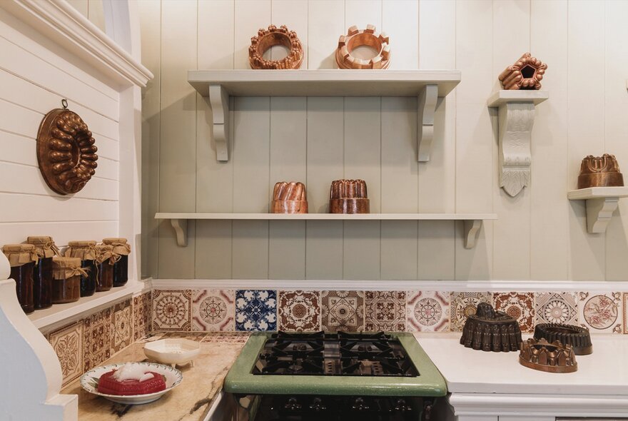 Heritage home kitchen with old gas range, shelves and tiling with copper baking moulds.