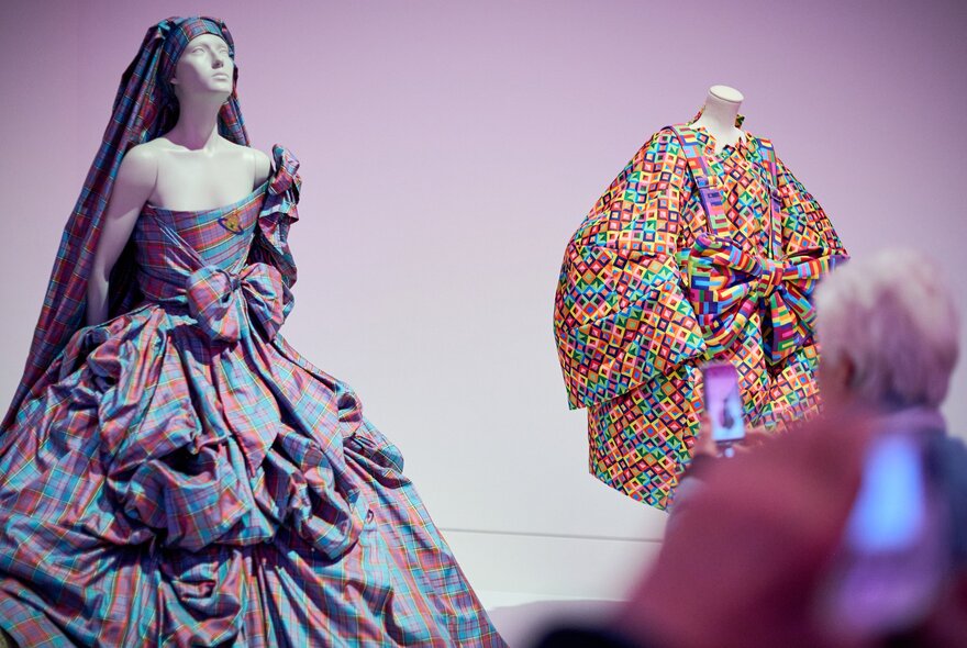 A mannequin in a gallery wearing a gown made of purple tartan fabric and a tartan veil. 