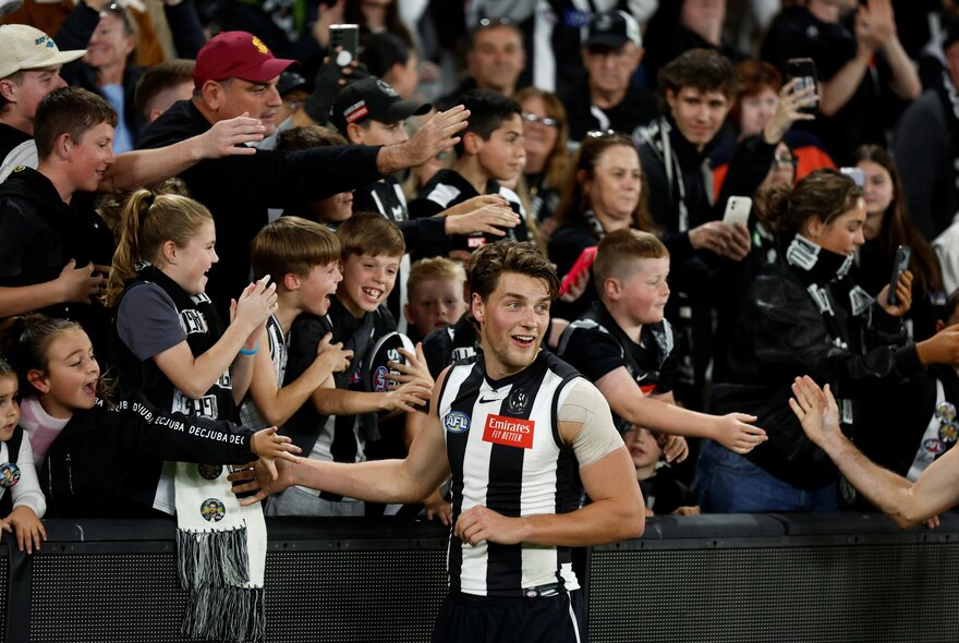 Collingwood AFL players engaging with their fans in the stadium.