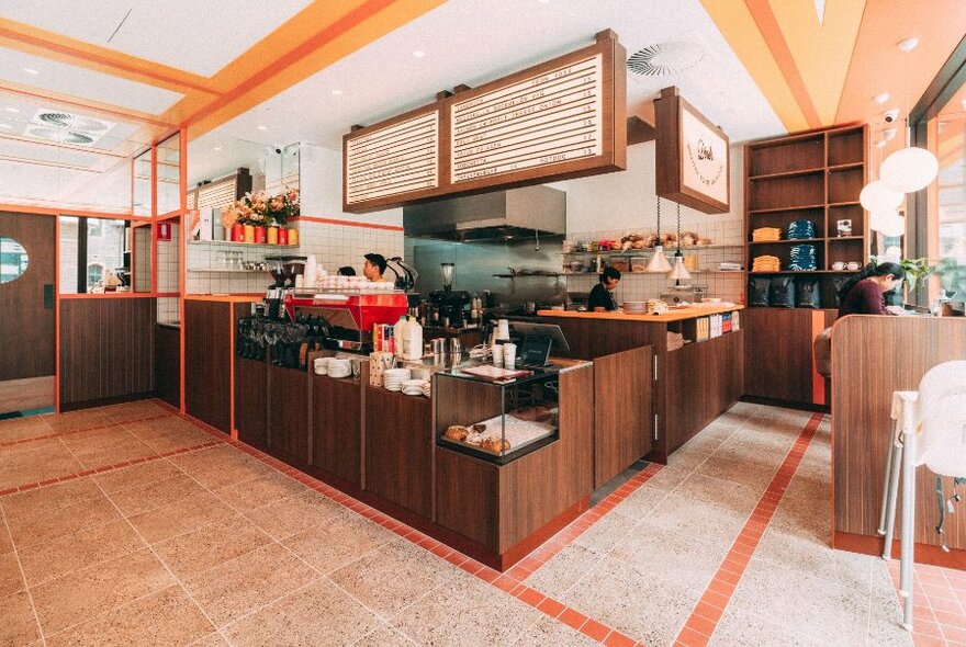 Cafe interior with display cabinets, coffee machine and signage.