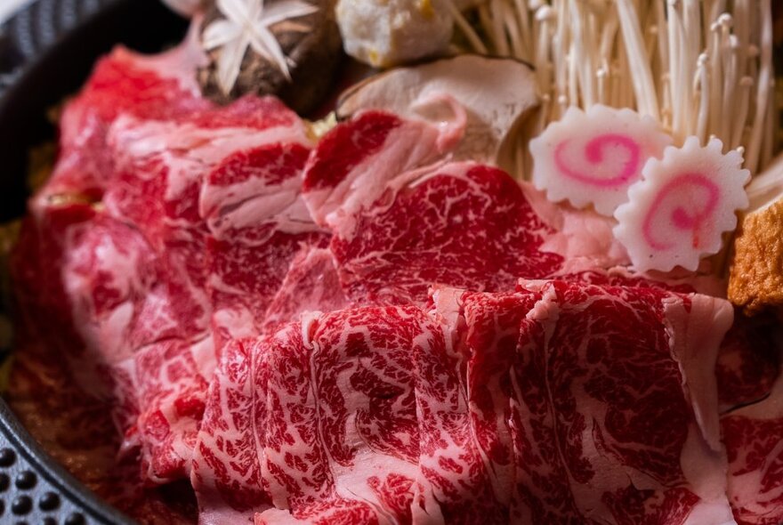 A plate of wagyu meat with mushrooms and garnishes.