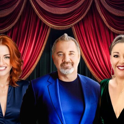 Two women and a man in front of a stage with draped velvet curtains.