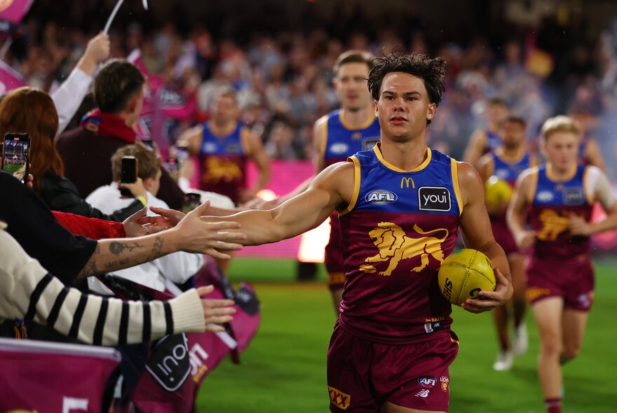 Lions AFL players greeting fans in the stands during a match.
