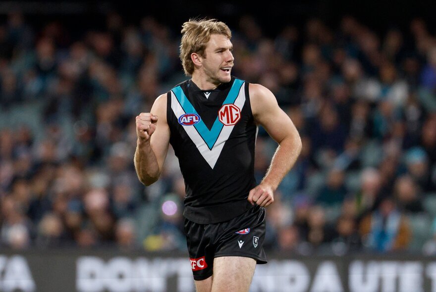 A Port Adelaide Power AFL player pumping his fist in celebration during a game.