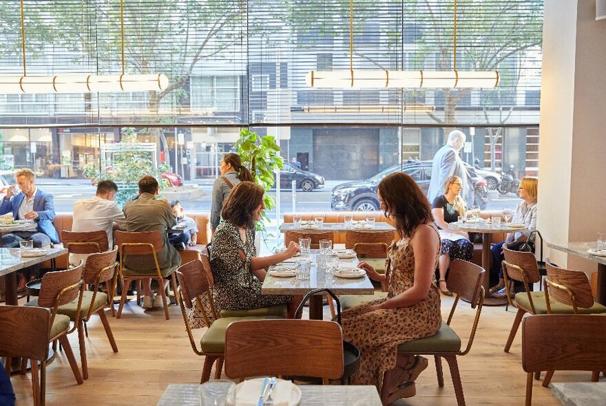 People seated in a restaurant with floor to ceiling window.