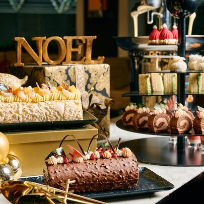 A Christmas buffet with yule log, small cakes, trifle cups and a sign saying NOEL. 