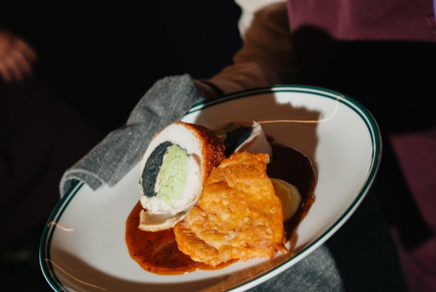 Looking down at an oval plate of food showing a cross-section through the middle and a red sauce. 
