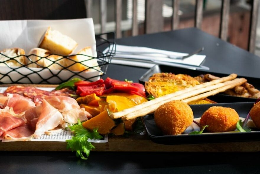 Rectangular platter full of antipasti, on black table.