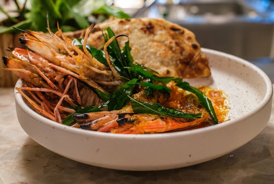 A prawn dish with bread and greens.