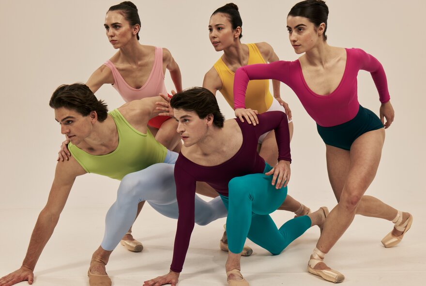 Five ballet dancers in a group pose, leaning gracefully and bending forward, all dressed in vibrant, contrasting dancewear.