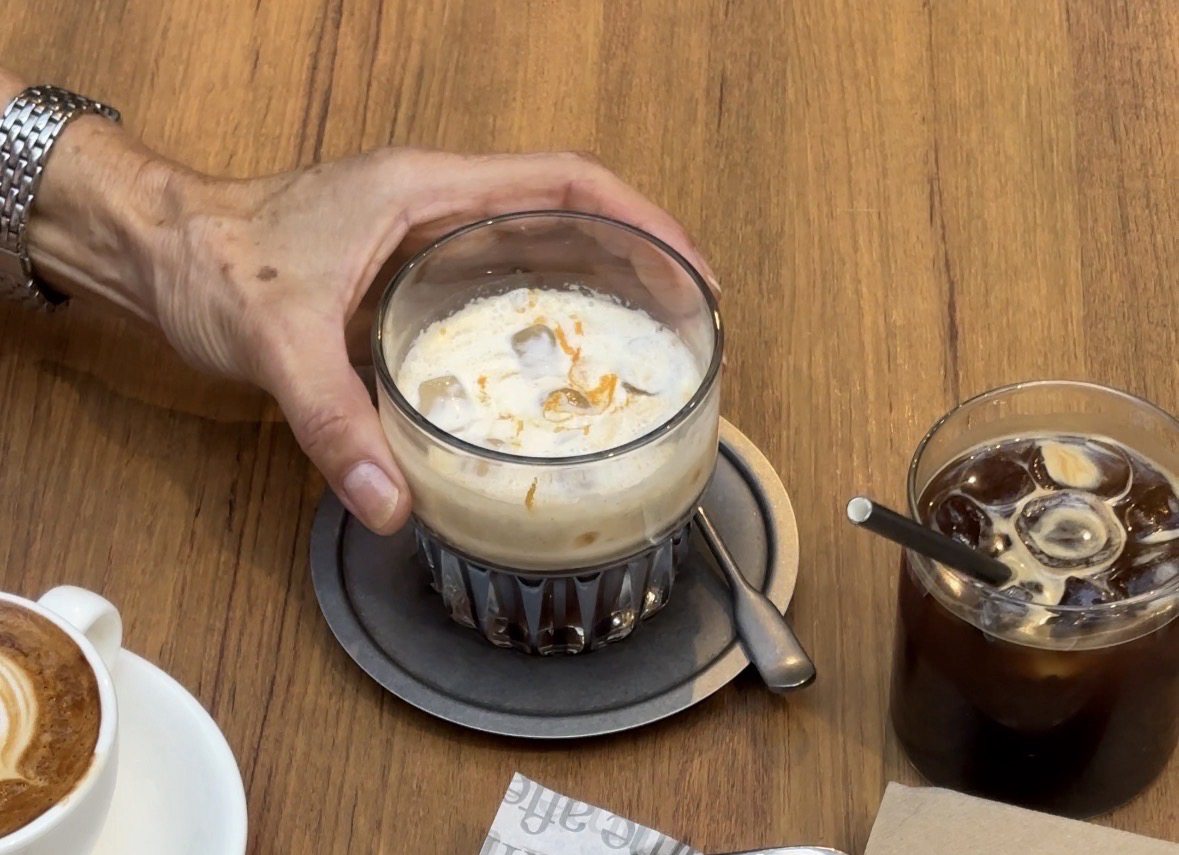 A hand holding a creamy iced coffee.