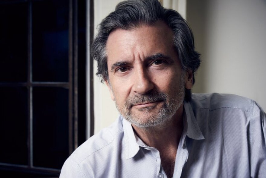 Actor Griffin Dunne with beard and wearing blue shirt.