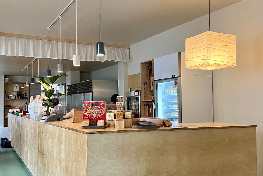 Cafe interior with large wooden serving counter, and produce on display.