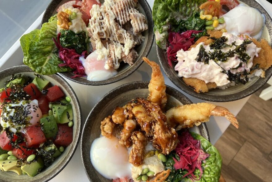 Bowls of food including egg based breakfast dishes, a salad, and tempura.