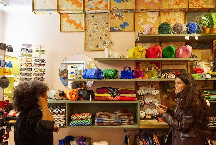 Two women trying on accessories in a colourful fashion boutique.