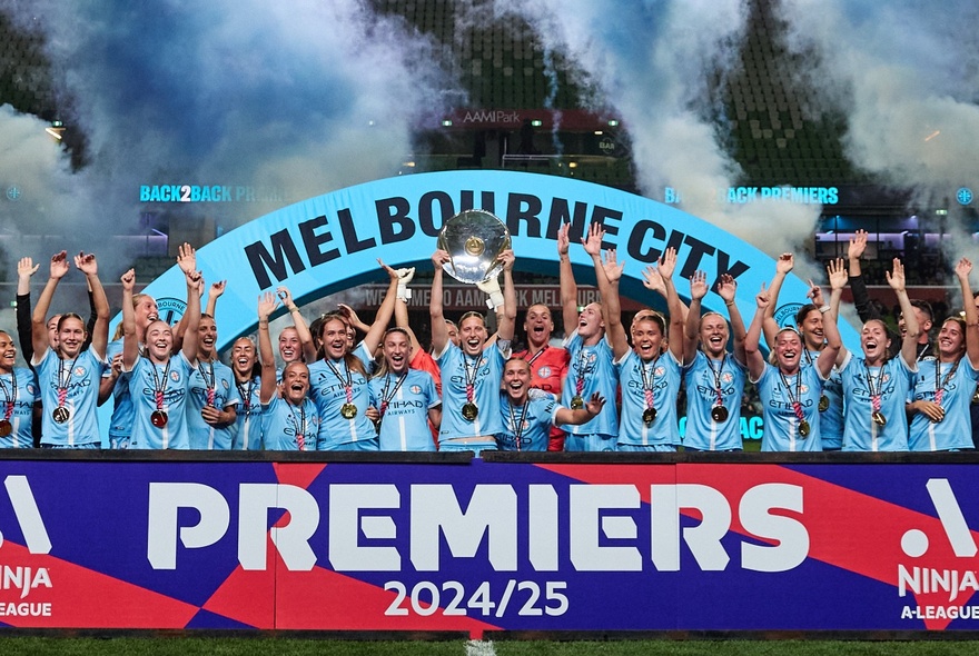A mens soccer team in pale blue kit celebrating with signs and flares.