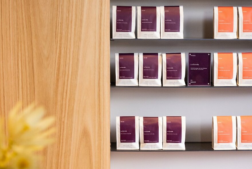 Wall displaying bags of coffee beans to purchase, on shelves.