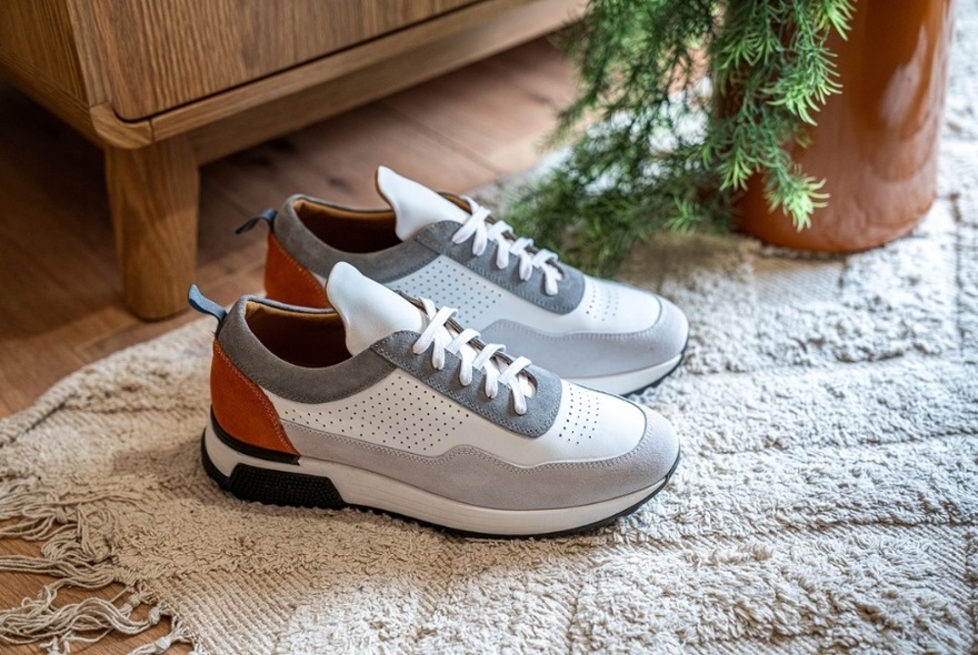 Pair of white runners on a white rug with wooden cabinet and poplin to rear.