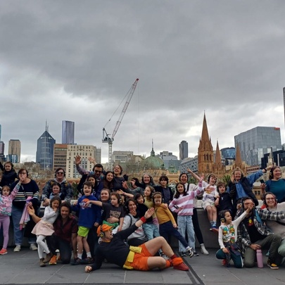 Flash mob tour group gathered on a rooftop with Melbourne buildings and storm clouds in the background.