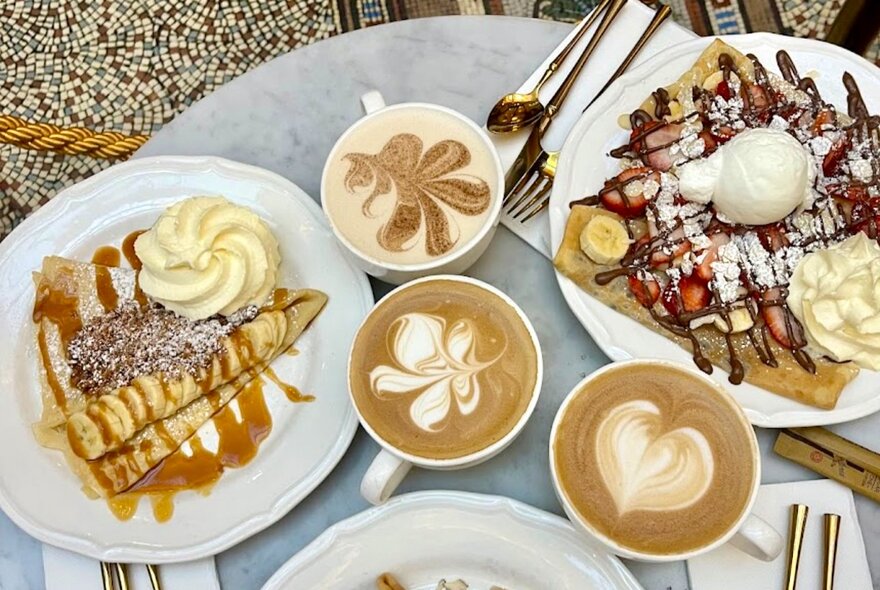 A brunch spread featuring crêpes with chocolate and cream alongside latte art coffee.