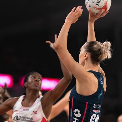 A Melbourne Vixens netballer holds the ball above her head as she prepares to take a shot at goal.