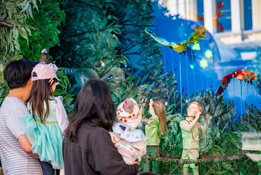 A family looking at a window display with puppets of Bindi and Bob Irwin bird watching.