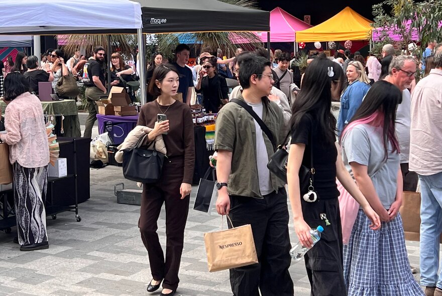People at an outdoor market wandering around the marquees.