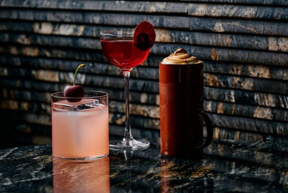 Three cherry-themed cocktails against a tiled background.