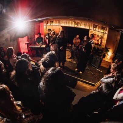 Fish-eye lens view of a mall venue with musicians on a small stage surrounded by audience.