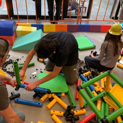 Kids sitting on the floor building with play construction equipment.