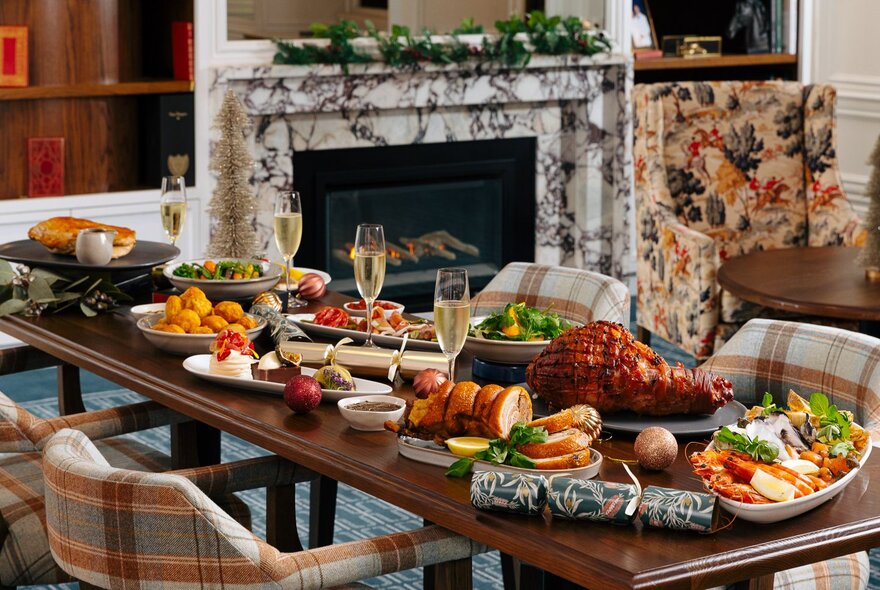 A dining table in a club laden with a Christmas feast including platters of roasted vegetables, ham, roast turkey, salads, and glasses of wine.