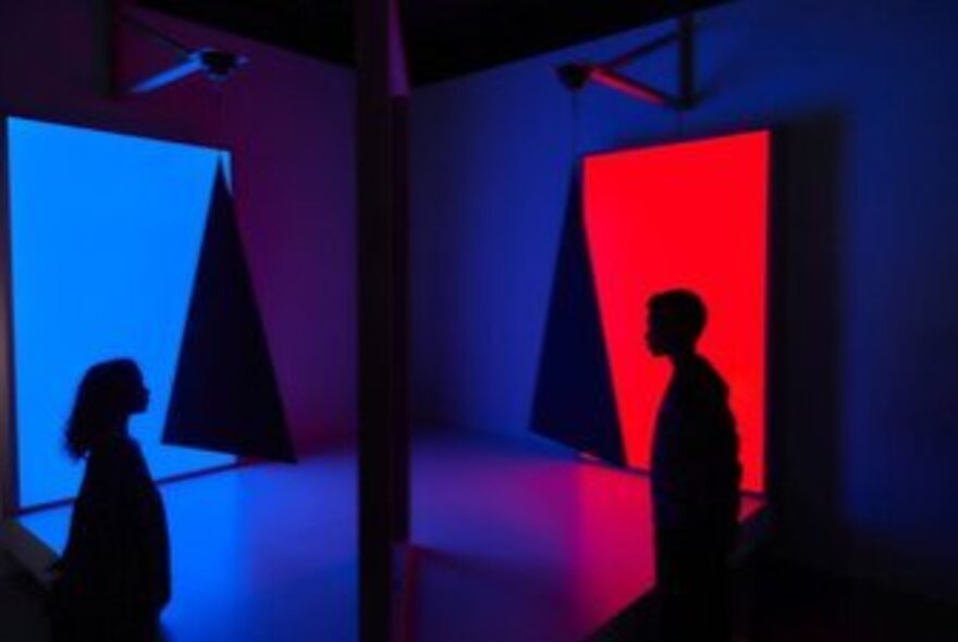 Dark silhouetted figures in a space with red and blue lighting.