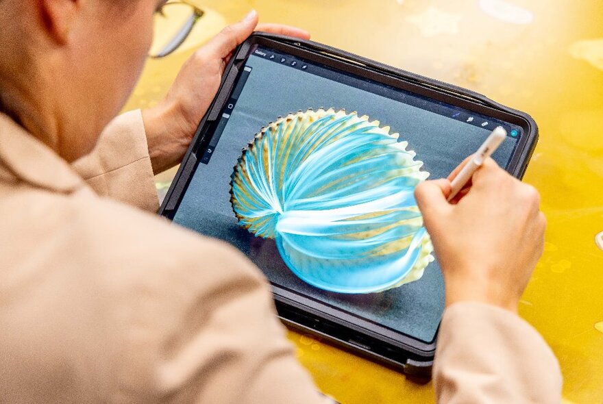 Looking over the shoulder of someone holding an iPad and drawing with a stylus.