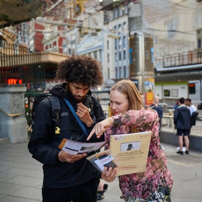 Participants with casebook paperwork looking for clues in the city.