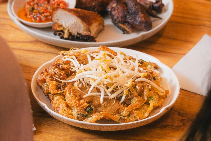 An Indonesian fried dish with bean shoots on top as garnish.