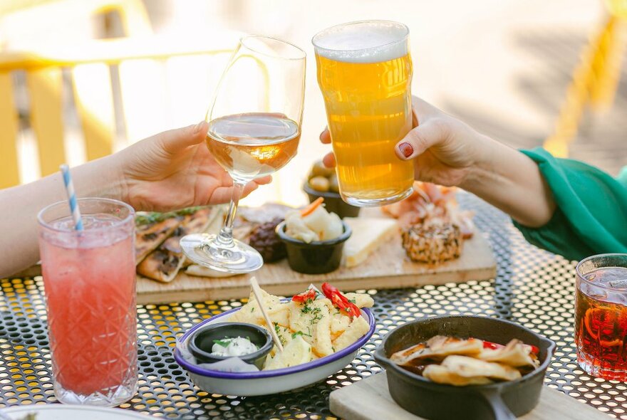 Two friends are doing a cheers with a beer and a wine