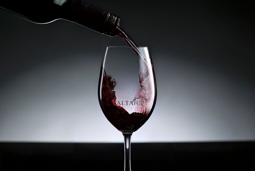 Red wine being poured from a bottle into a wine glass.